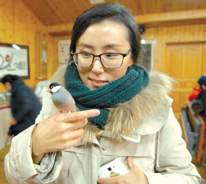 마술공연장을 찾은 방문객이 작은새를 손위에 얹고 즐거워 하고 있다.